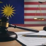 A symbolic image of a gavel, a Malaysian flag element, and a performance review document, representing the intersection of law and HR practices in Malaysia.